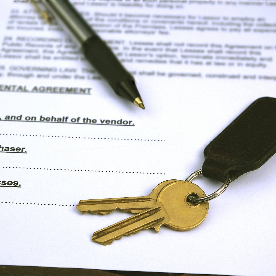 Keys on a keyring beside a pen and a document labeled "Rental Agreement."